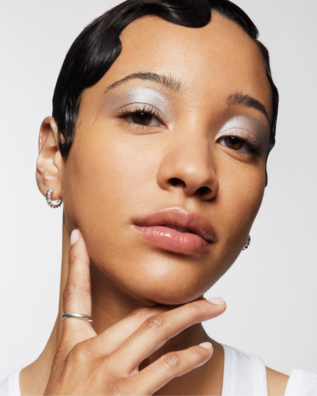 Model wears Milk Makeup Future Fluid Concealer with silver eyeshadow for a medium-to-full coverage finish