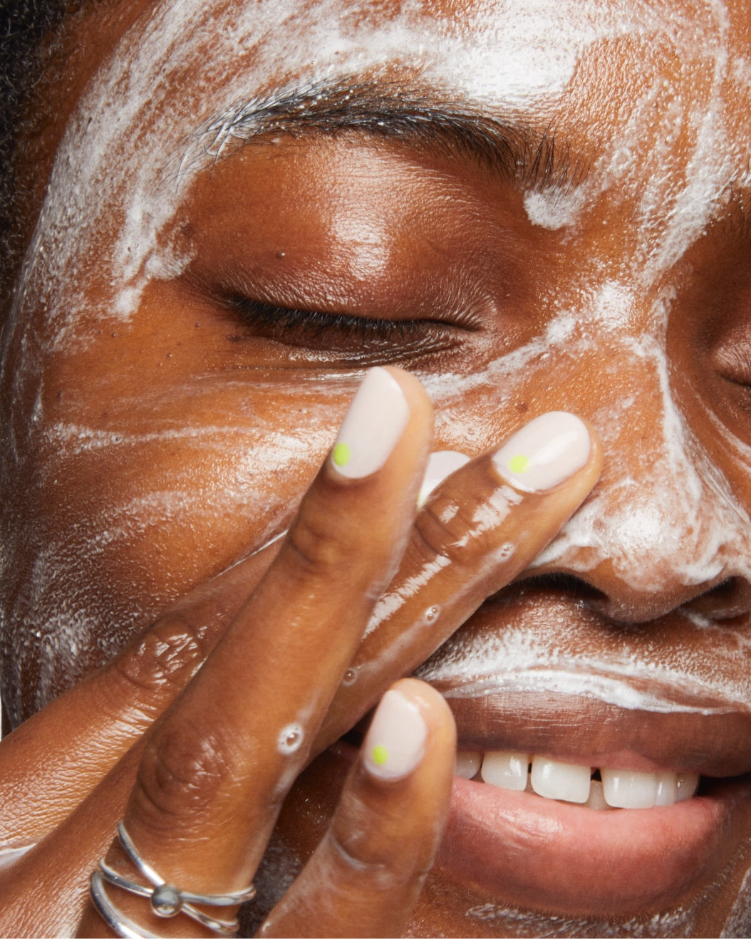 Close-up of model washing her face with lathered cleanser
