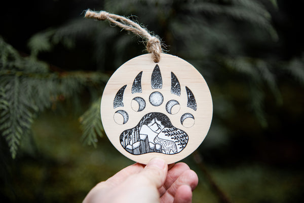 A wooden circle ornament with a black and white bear paw ornament on it
