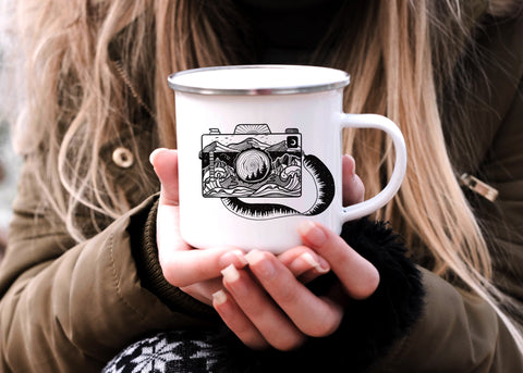 A woman holding an enamel cup with illustrated camera on it in front of her 