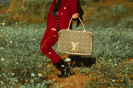 Un modèle marchant à l'extérieur affiche un sac à main Lous Vuitton