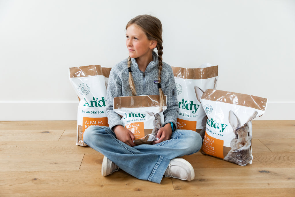 girl with packages of andy alfalfa pellets for young rabbits