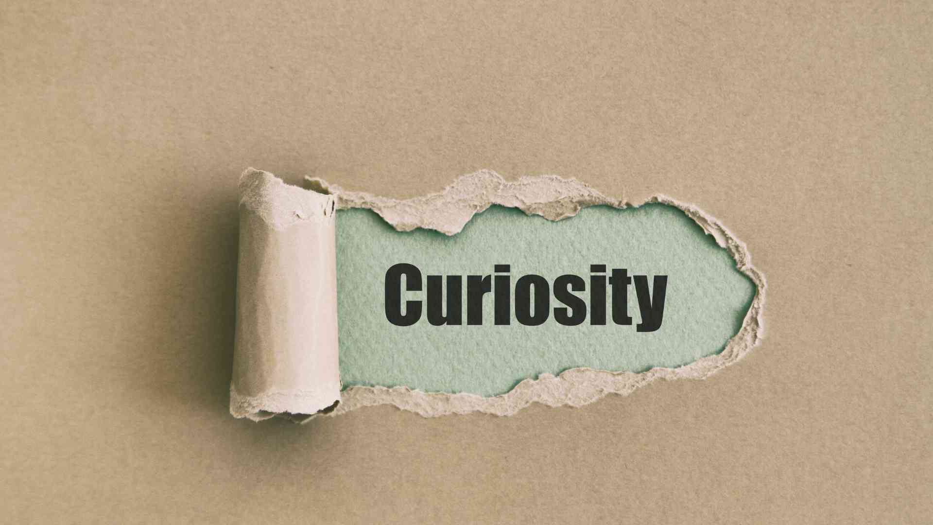 The word "curiosity" revealed from a torn brown paper.