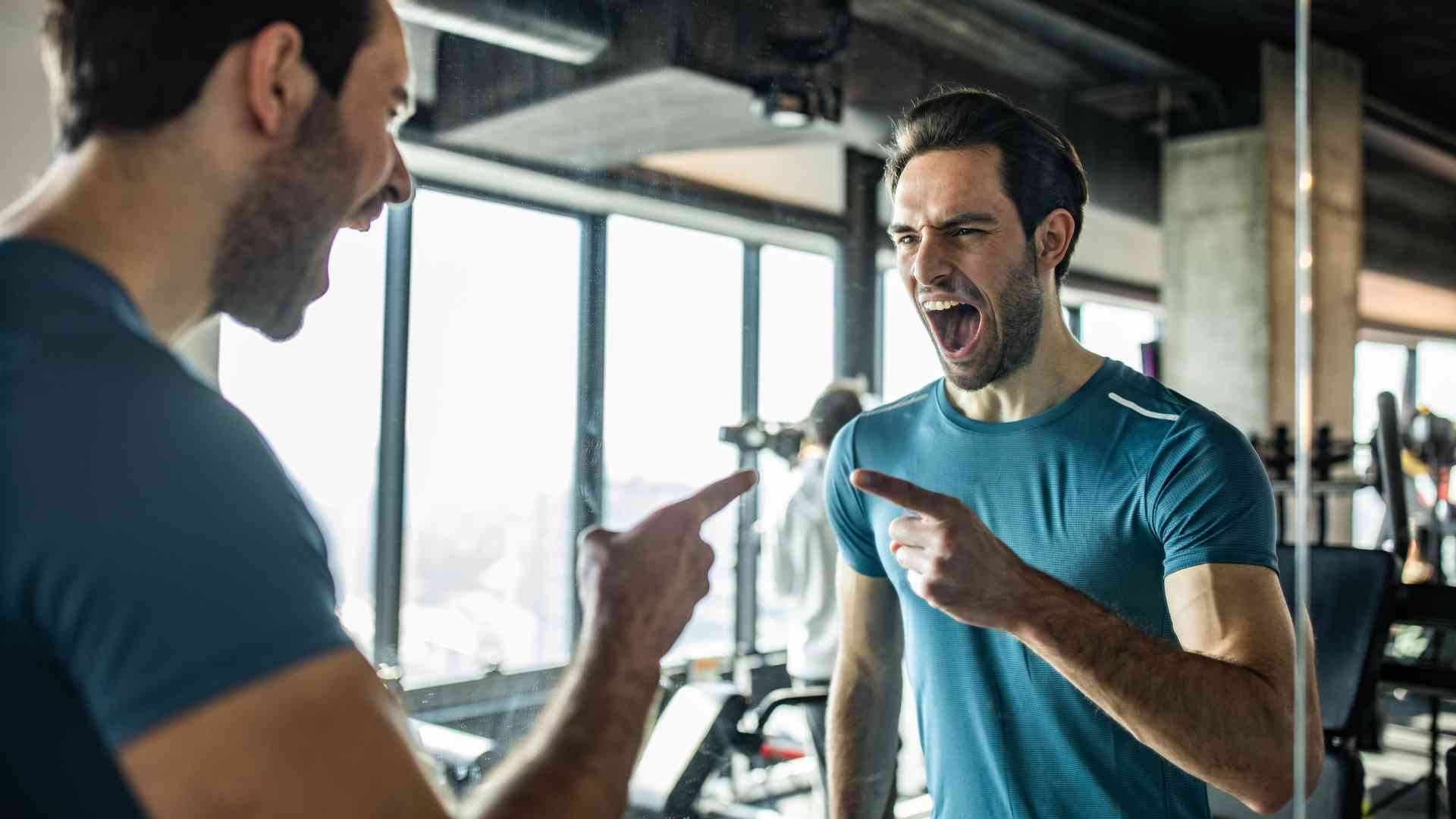 A motivated man at the gym talking to himself in front of the mirror.