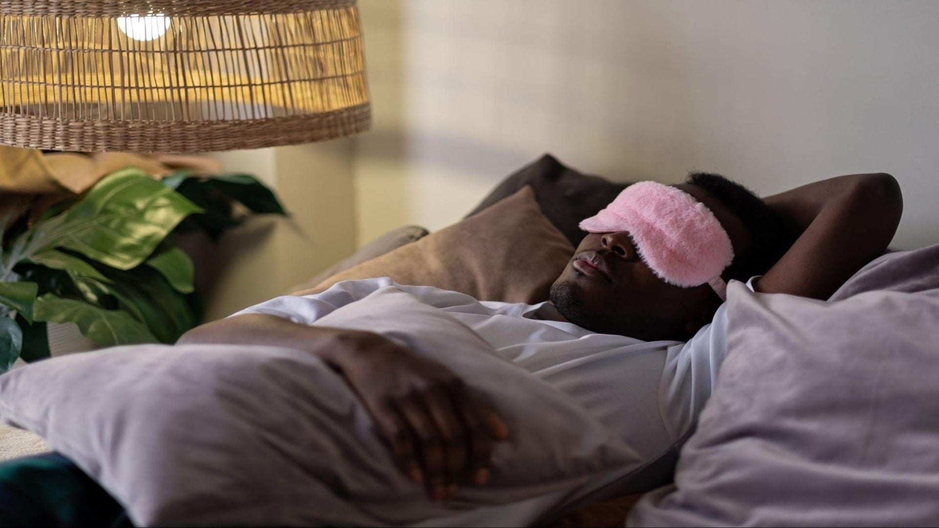 Man sleeping while wearing a pink sleeping mask