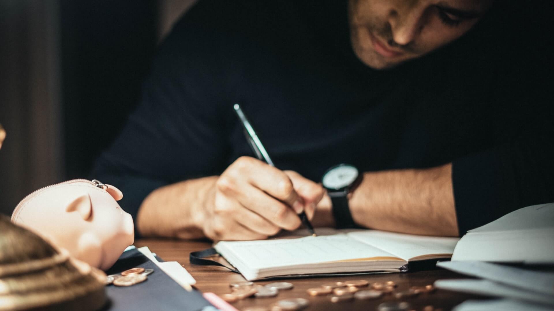 Man taking down notes on a messy table