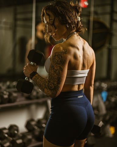 vrouwelijke bodybuilder voor spiegel met dumbells