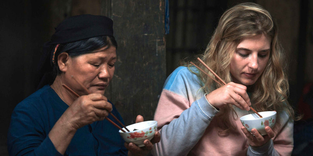 Asiatische und weiße Frau essen mit Stäbchen aus einer Schüssel