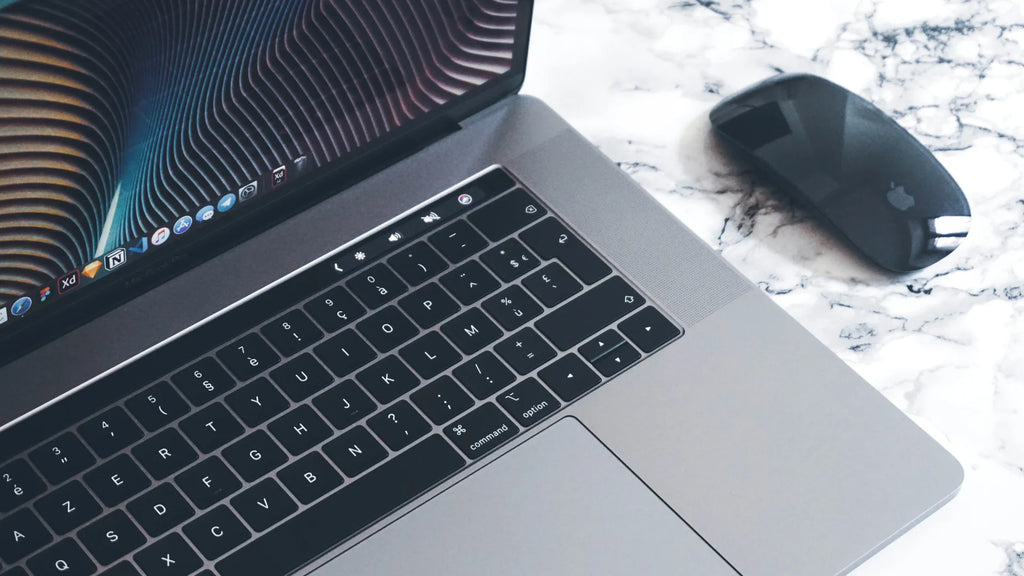 Macbook next to a black magic mouse