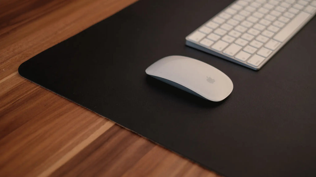 apple magic mouse on mouse pad next to apple magic keyboard