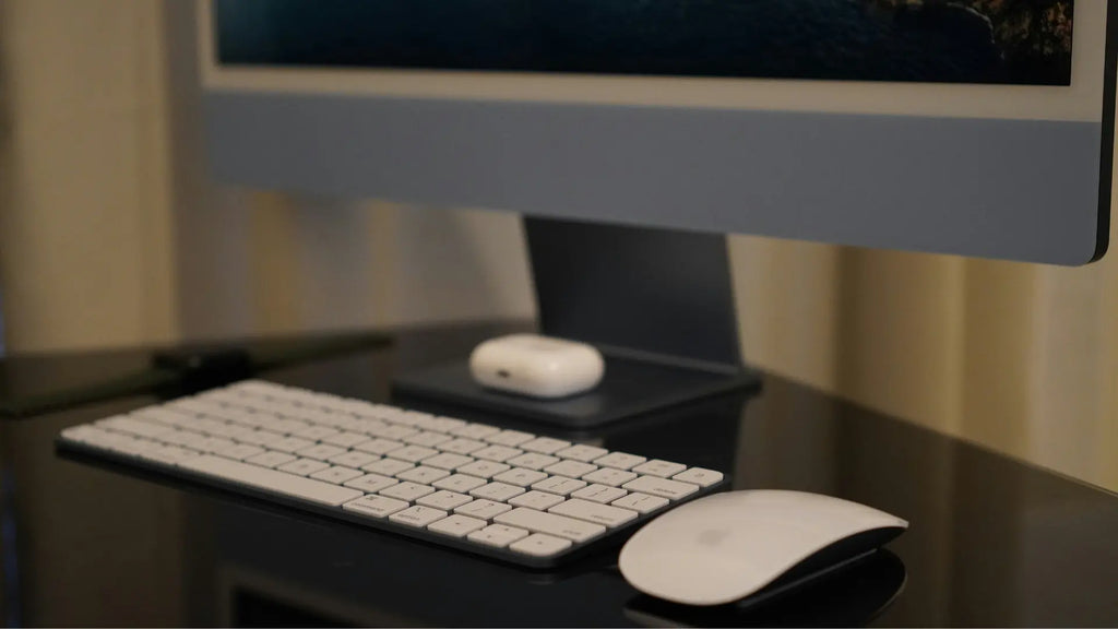 magic mouse next to a keyboard and desktop