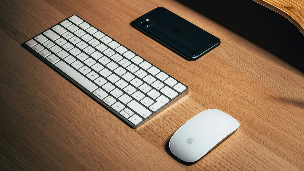 magic mouse next to keyboard on wood- desk