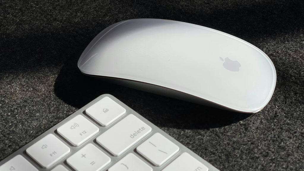 white apple magic mouse next to keyboard