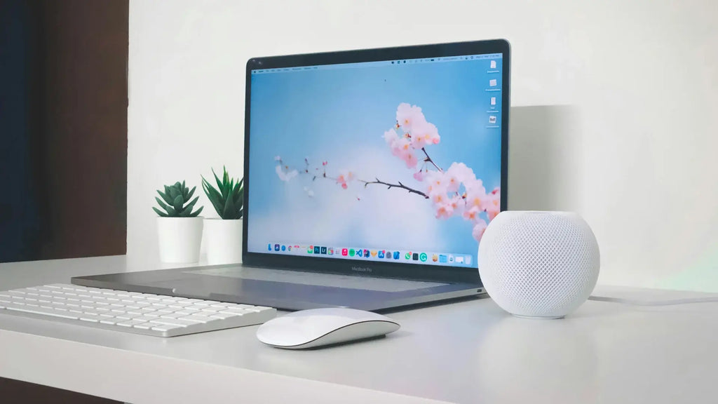 A workdesk with a Macbook, an Apple Homepod and a Magic Mouse