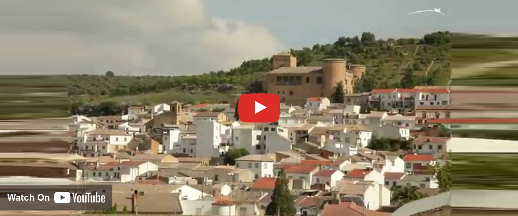 Castillo de Canena castle with hilly groves behind overlooking the village below.