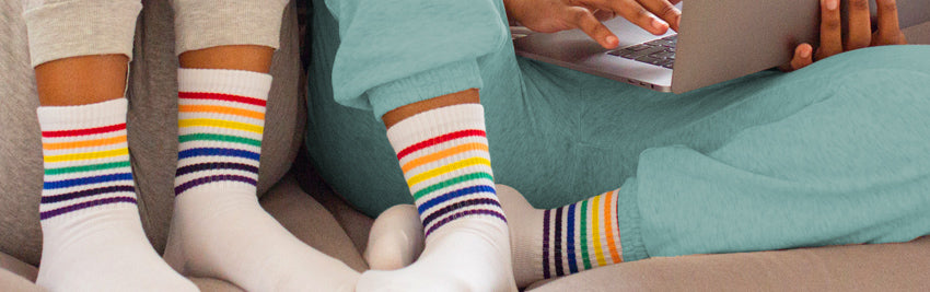 Two people wearing white socks with a rainbow stripe