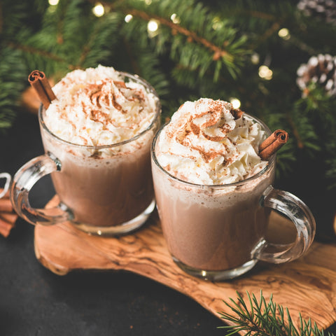 Hot Chocolate in glass mugs with festive Christmas background