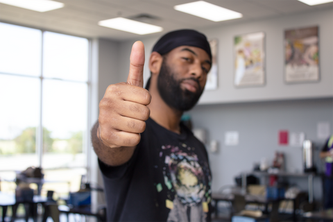 Man giving thumbs up to camera in cafeteria