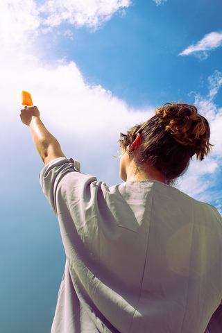 Girl holding popsicle up into sky