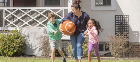 Mom and two kids running with giant inflatable football.