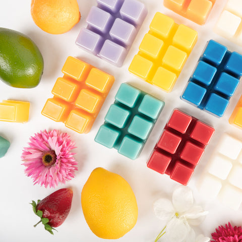 Colorful wax melts, fruits and flowers on a white table