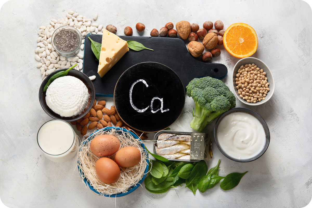 Vielfältige Auswahl an calciumreichen Lebensmitteln, einschließlich Käse, Nüsse und verschiedene Gemüsesorten, arrangiert als Anschauungsmaterial über die Bedeutung von Calcium für die Gesundheit und zur Unterstützung einer ausgewogenen Ernährung.