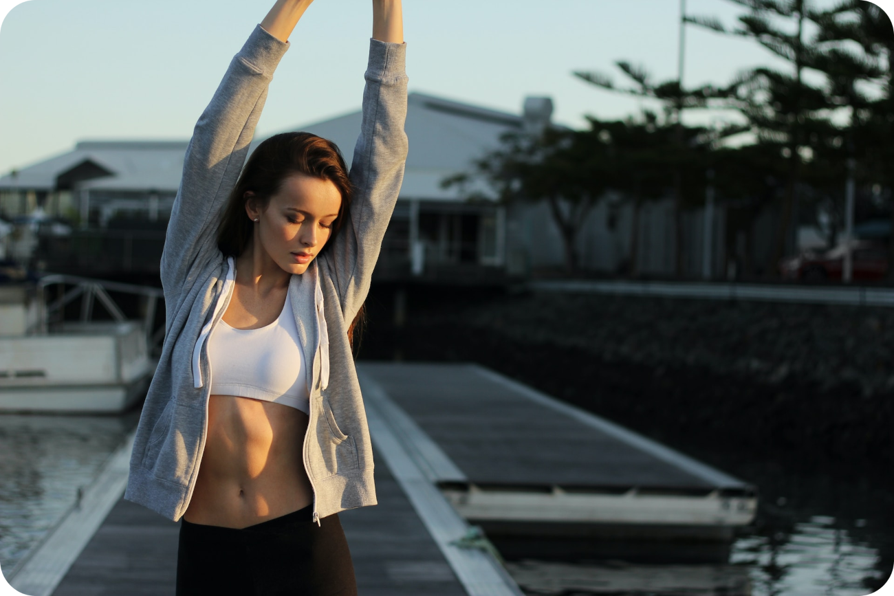 Frau in einer Dehnübung stehend, verkörpert die Bedeutung von Stretching und Bewegung am Morgen als wesentlichen Bestandteil einer erfolgreichen und energiereichen Morgenroutine für einen gesunden und aktiven Tagesstart.
