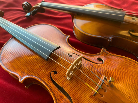 picture of a student violin and a professional violin next to each other on a table