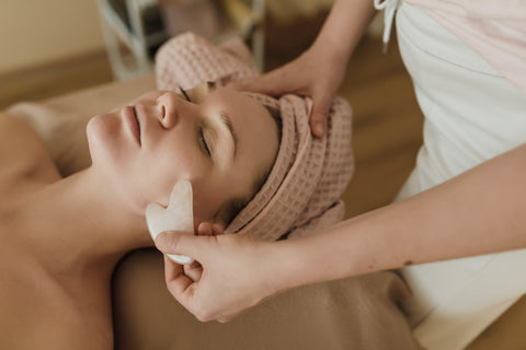 A woman having a facial with the gua sha and essential oils.