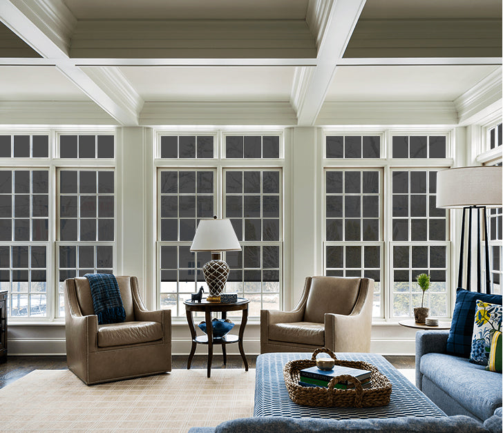 The living room is open and tidy, and the windows are blocked by outdoor shades.