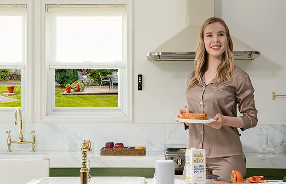 A smiling woman hold a plate of bread passing thru the kitchen.