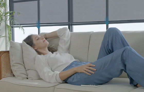 A woman lying at the sofa, hands-free to control the motorized shades, and to feel the peace at the moment.