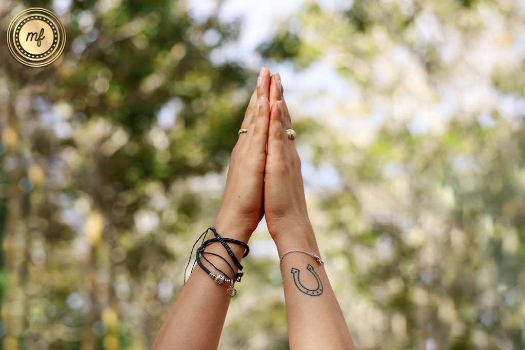 Two hands raised together amidst nature, as if practicing yoga