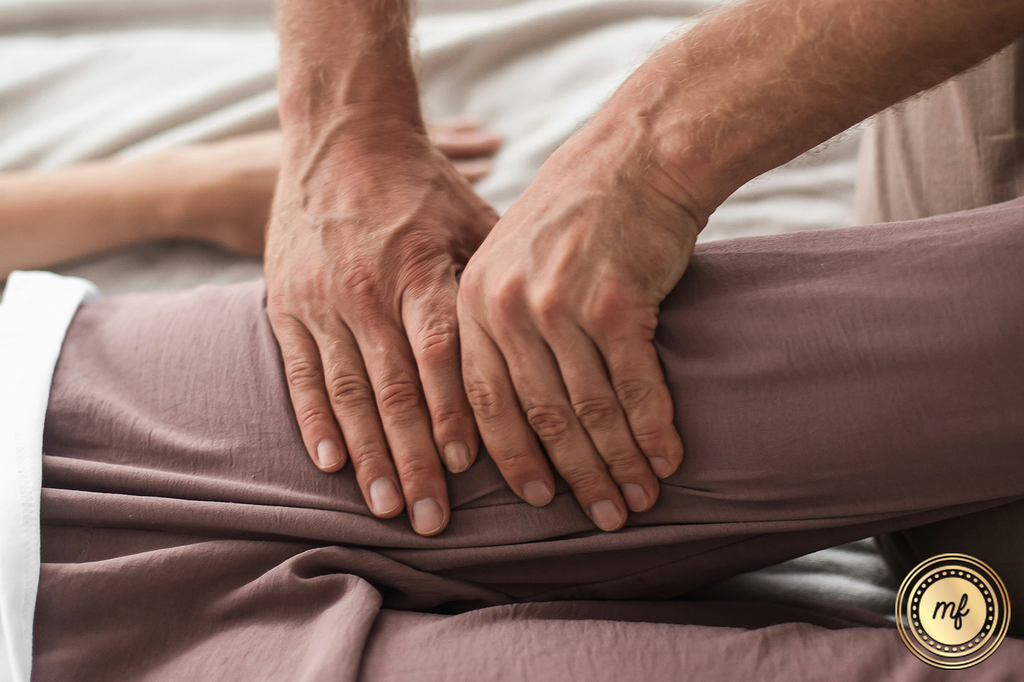 Hands massaging a woman's thigh.