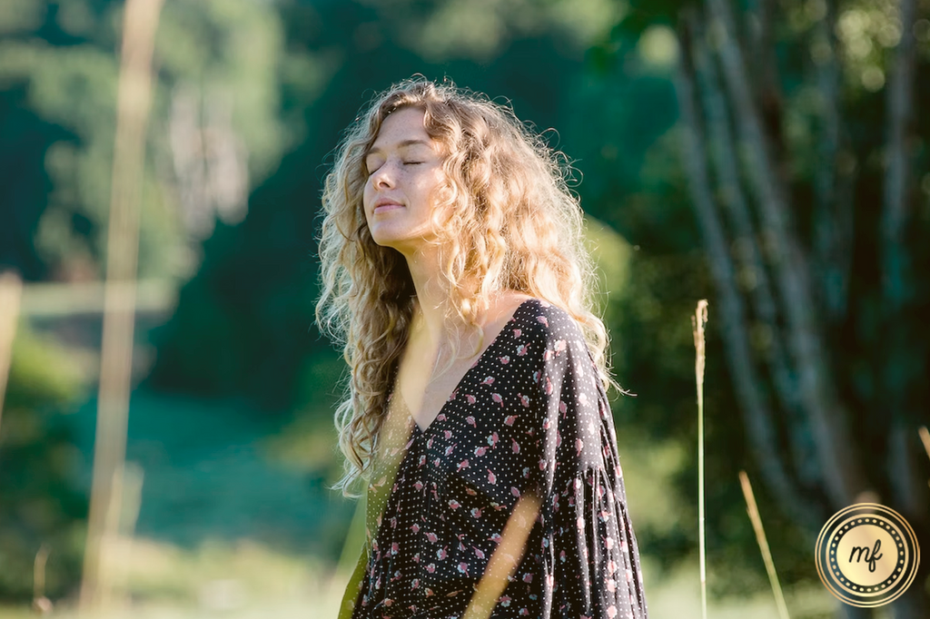 Woman with her eyes closed and a serene look outdooors.