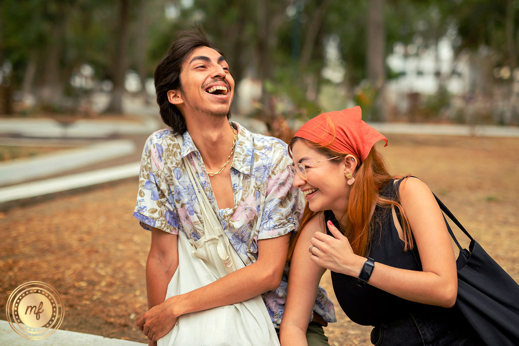Man and woman sitting on a park laughing.