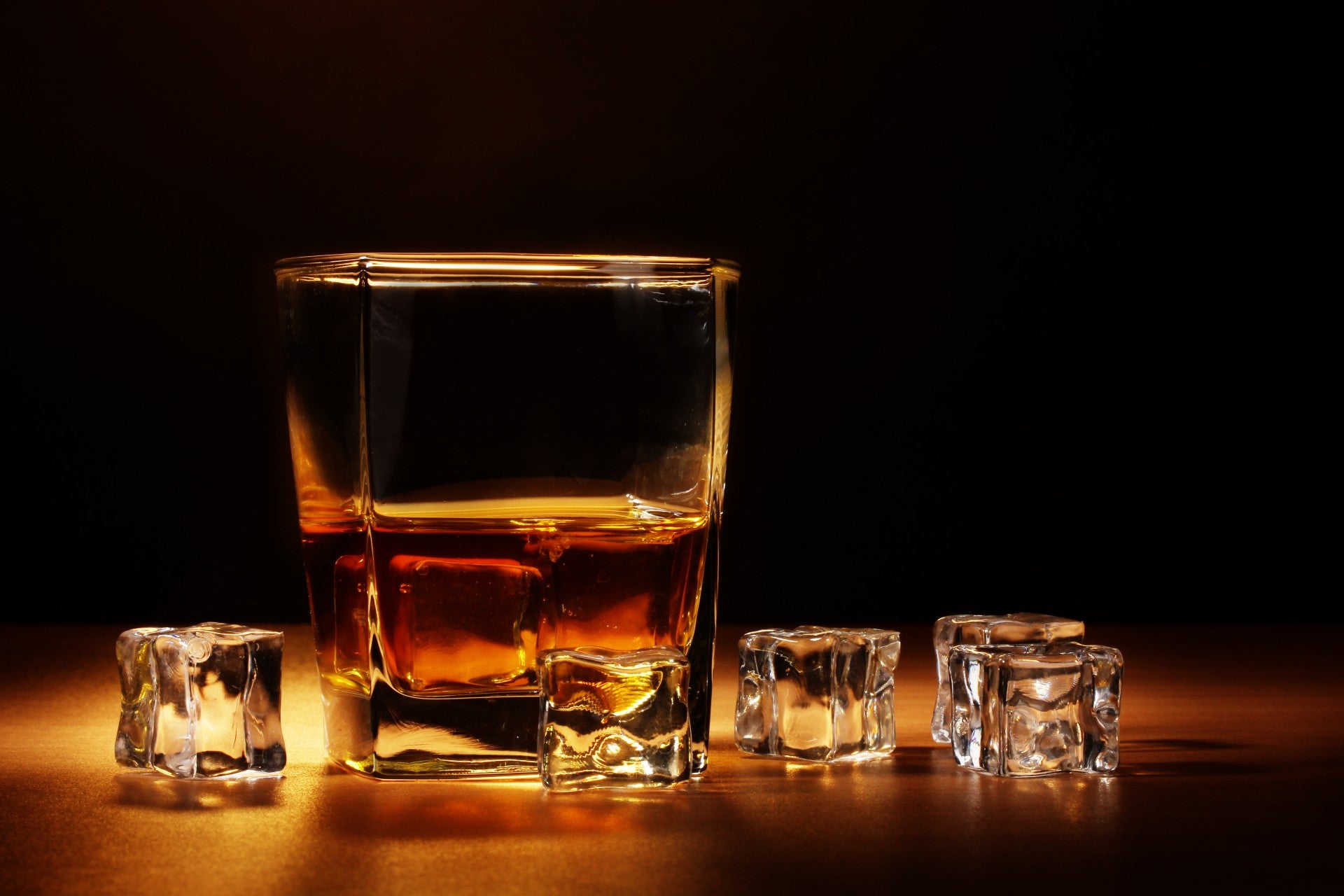 Premium Photo  Whiskey or bourbon in a rocks glass with a big ice cube  shot with hard light and harsh shadows bright backdrop copy space