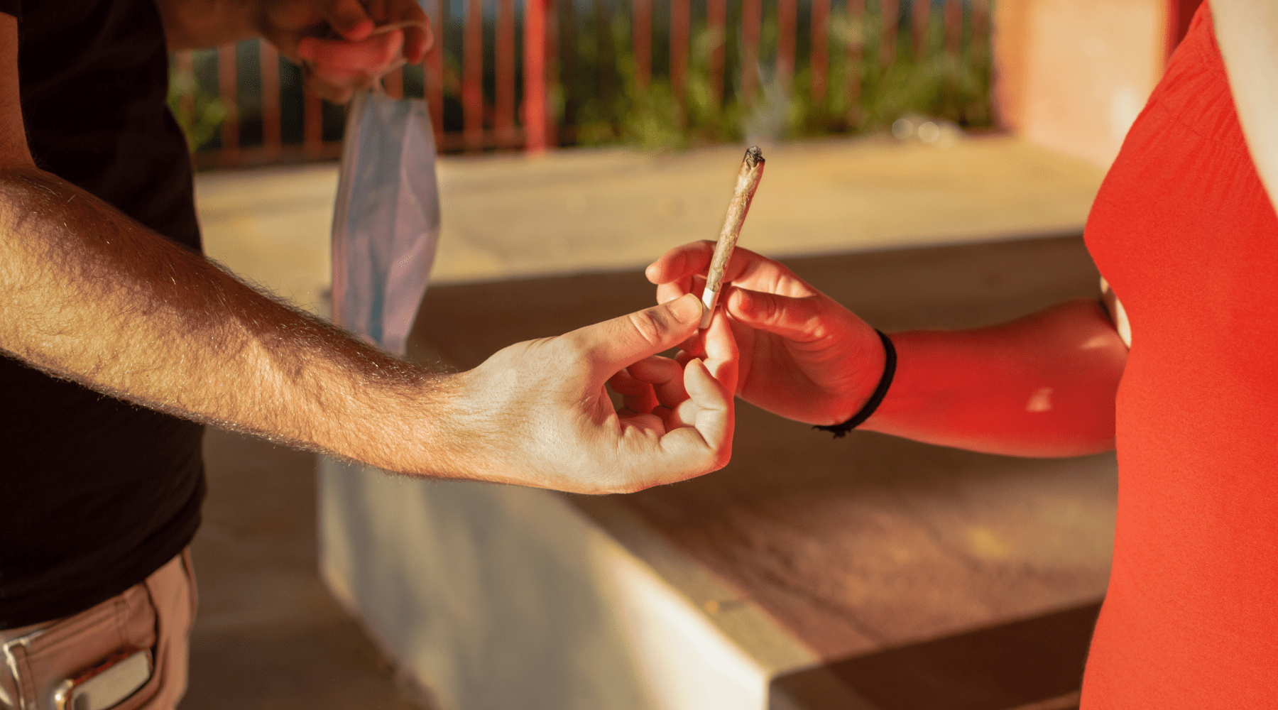 two people sharing a joint at sunset