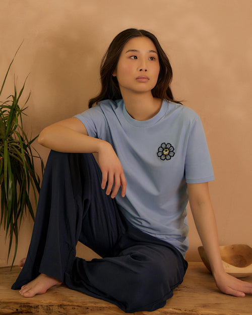 Women wearing a blue tee with an Appliqué embroidered sitting down 