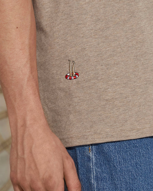 a man wearing a beige shirt with an embroidery 