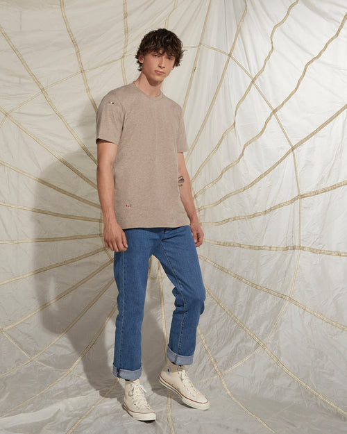 a man wearing a beige shirt with an embroidery 