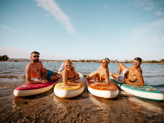 Group of four friends on their paddleboards by the beach