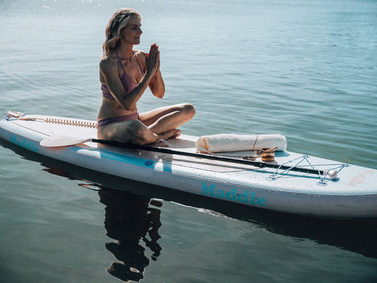 woman meditating on sup board