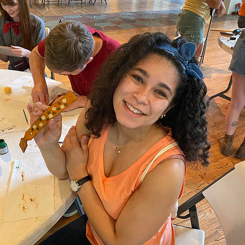 student showing of their leather keychain design with small white flowers and green leaves