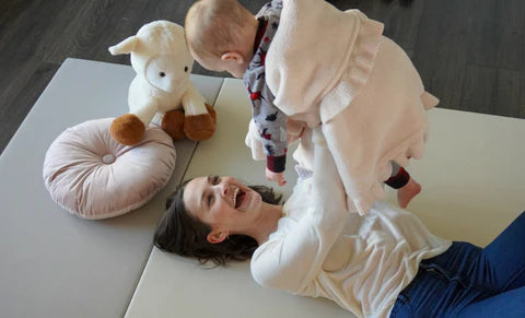 Mother carrying a baby while lying on an ALZiP Play Mat