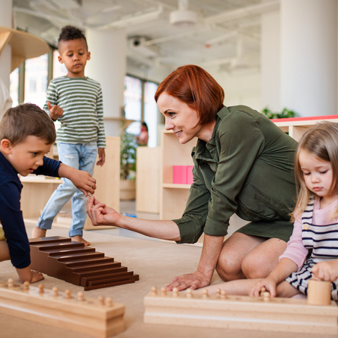 Three Kids around a teacher showcasing a Montessori classroom