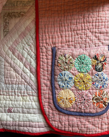 A close-up of a pink quilt coat pocket adorned with Suffolk puffs/yoyos