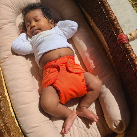 image of baby sleeping in orange diaper