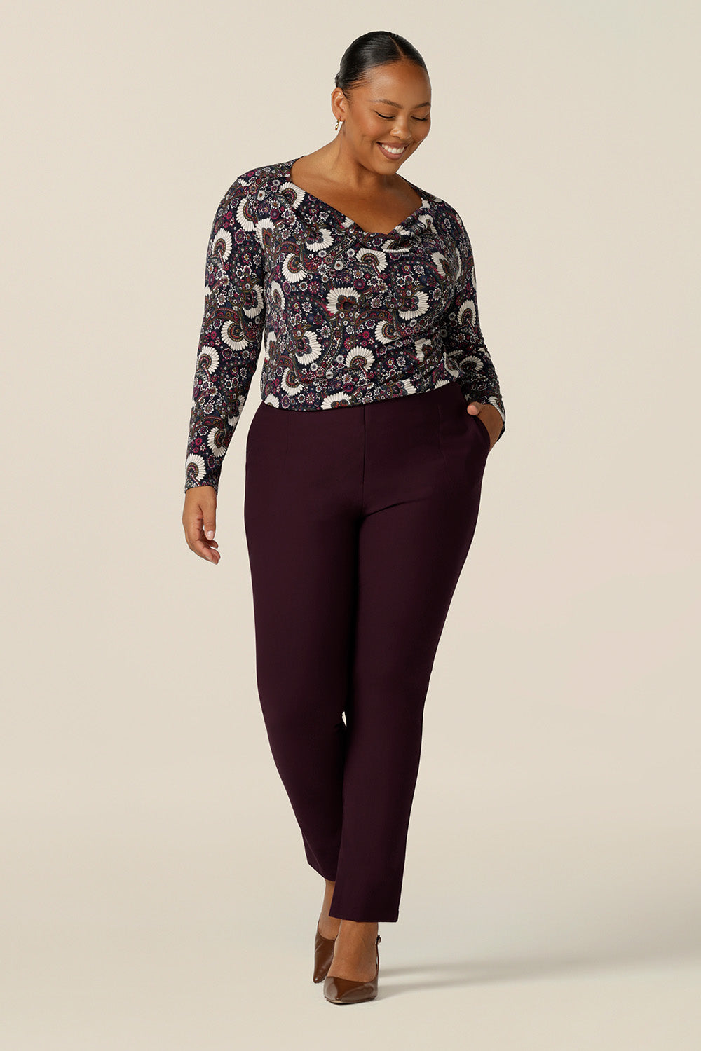 a plus size woman wears a long sleeve, cowl neck top in paisley print jersey, size 18. A great work top, the Chrissy Top is worn with slim leg tailored work pants in Mulberry, both of which are made in Australia by Australian and New Zealand women's clothing label, L&F.