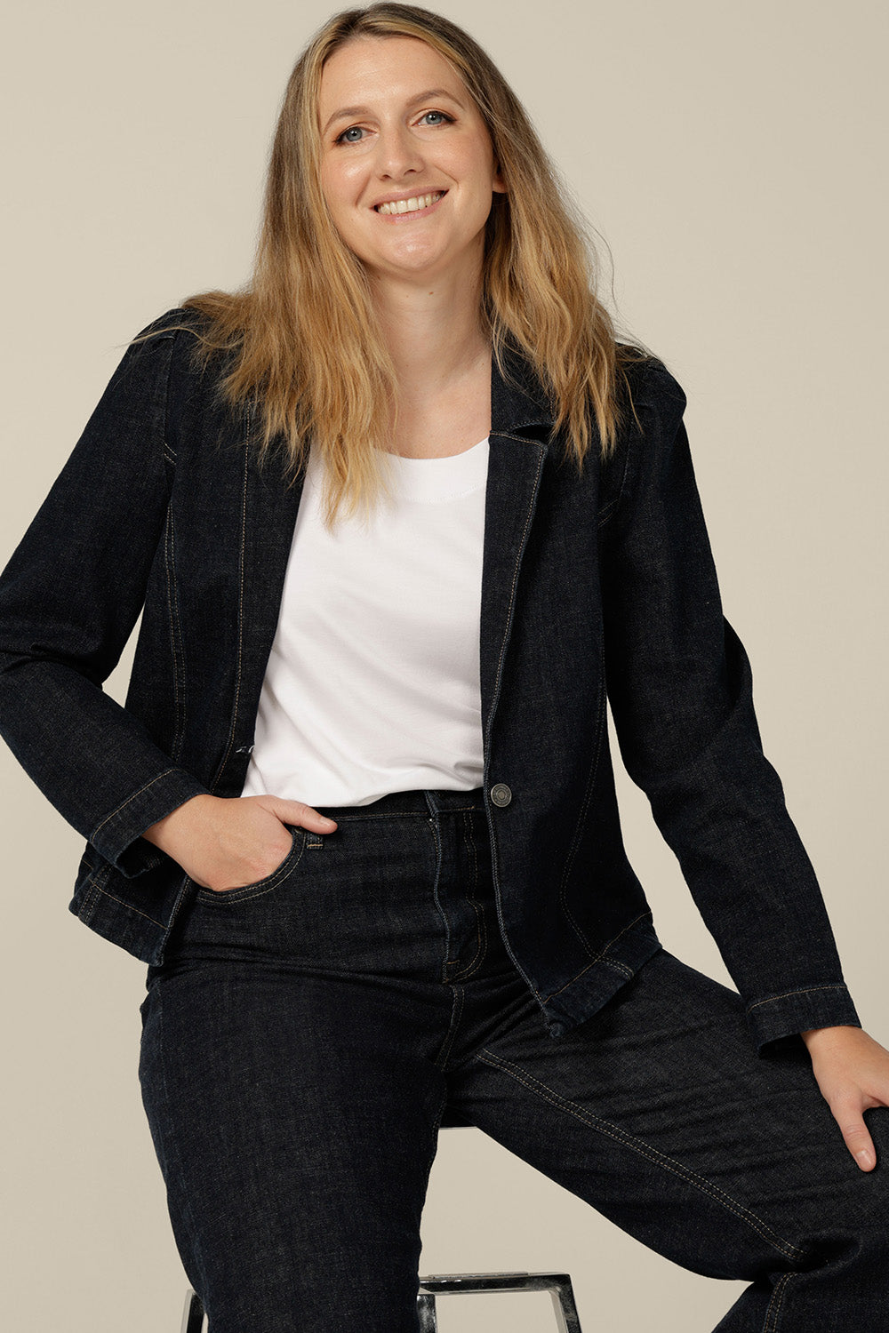 A size 12 woman wears a denim blazer-style jacket by Australian and New Zealand women's clothing label, L&F. Worn with high-waisted, flared cut jeans in comfort stretch denim, this  denim jacket is tailored to fit sizes 8 to 24.